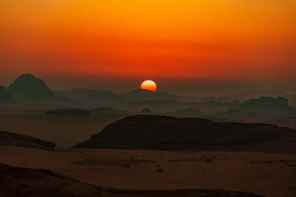 the sun is setting over the mountains in the desert